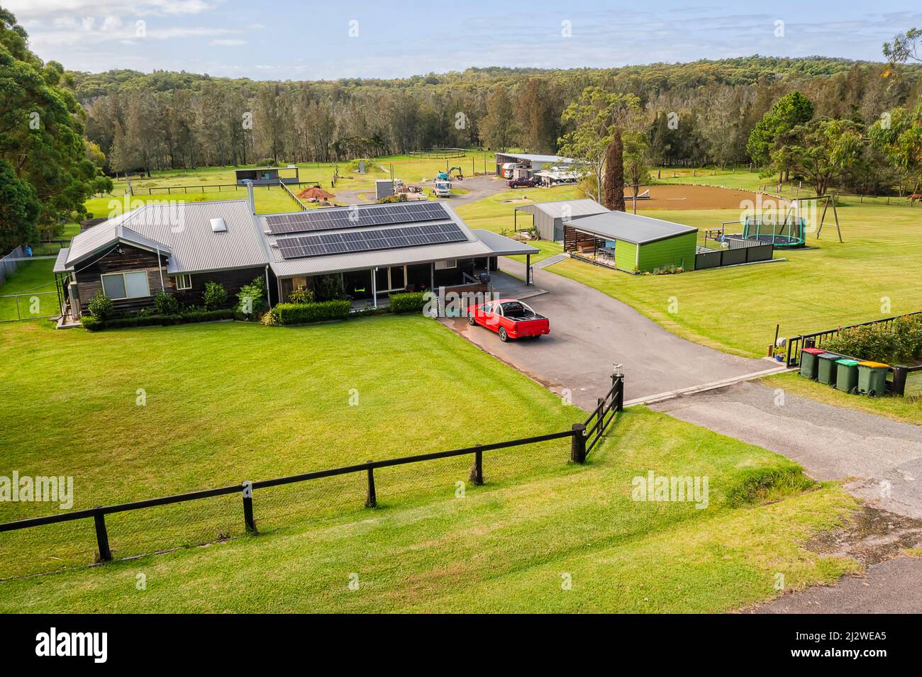 Abgelegene landwirtschaftliche Farm mit Pferdestall auf grünen Rasenweiden - erhöhte Aussicht. Stockfoto