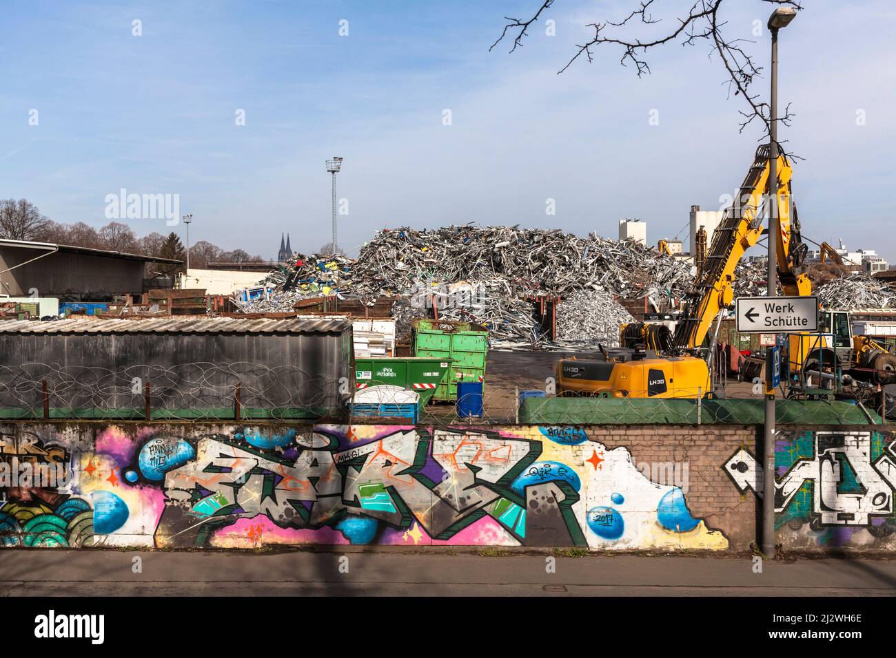 Schrottplatz mit altem Metall im Stadtteil Deutz, im Hintergrund der Dom, Wand mit Graffiti, Köln, Deutschland. Schrottplatz mit Altmetall im Stockfoto