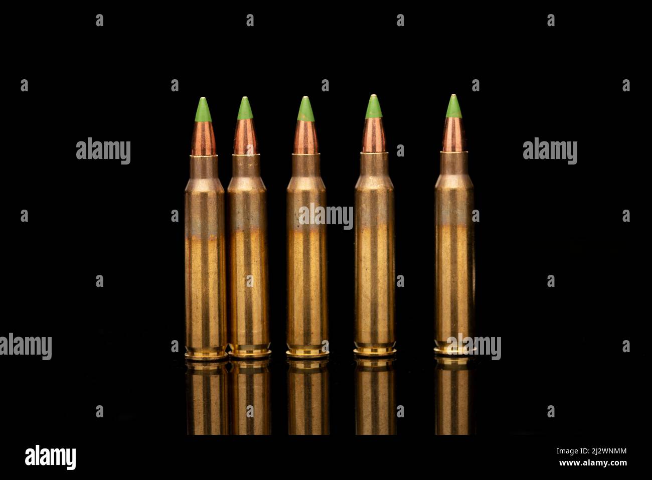 Eine Gruppe von 5,56 Kugeln mit grüner Spitze, die auf schwarzem Hintergrund in die Linie geordert wurden Stockfoto