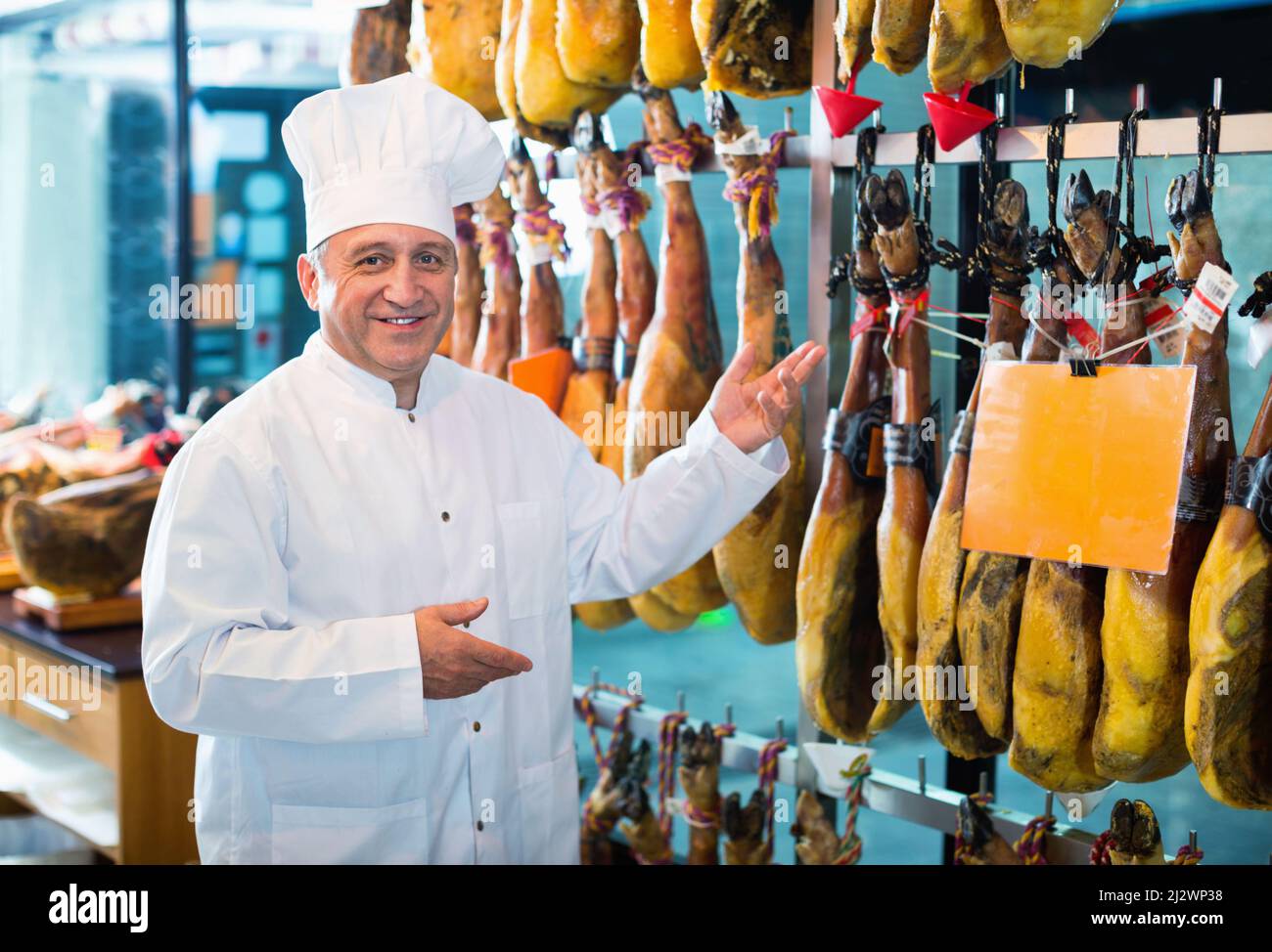 Porträt eines reifen Ladenmanns, der spanischen Jamon anbietet Stockfoto