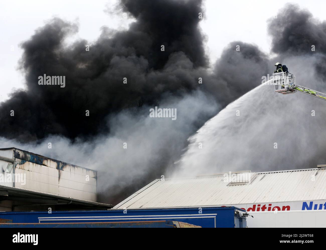 Mulheim, Deutschland. 04. April 2022, Nordrhein-Westfalen, Mülheim an der Ruhr: Die Feuerwehr löscht den Brand in einem Lagerhaus. Ein Kinderkarussell auf einem LKW-Anhänger hatte aus noch unbekannten Gründen Feuer gefangen. Aufgrund der starken Rauchentwicklung wurden Warnmeldungen über die Warnungs-App Nina veröffentlicht. Foto: Roland Weihrauch/dpa Quelle: dpa picture Alliance/Alamy Live News Stockfoto