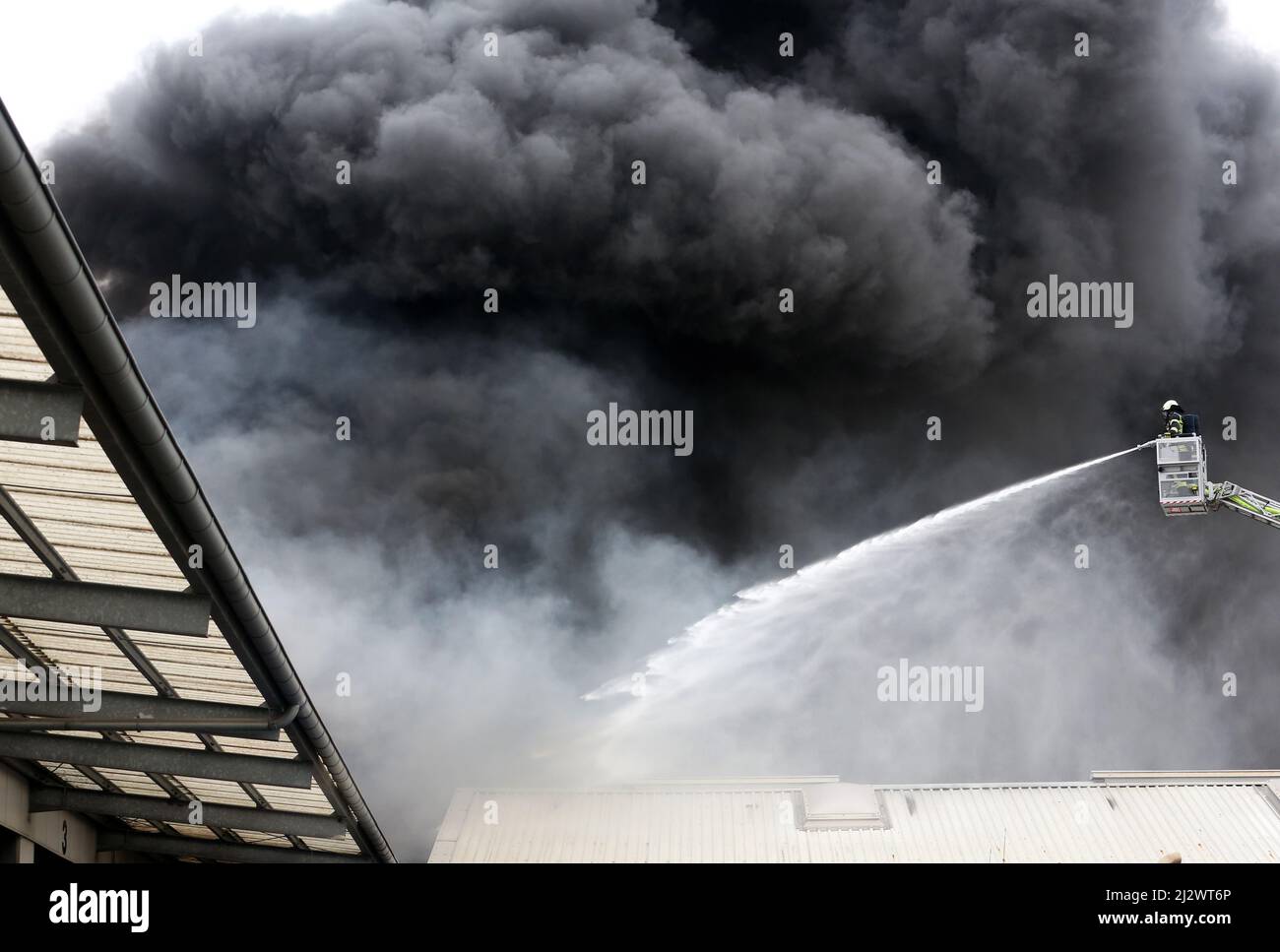 Mulheim, Deutschland. 04. April 2022, Nordrhein-Westfalen, Mülheim an der Ruhr: Die Feuerwehr löscht den Brand in einem Lagerhaus. Ein Kinderkarussell auf einem LKW-Anhänger hatte aus noch unbekannten Gründen Feuer gefangen. Aufgrund der starken Rauchentwicklung wurden Warnmeldungen über die Warnungs-App Nina veröffentlicht. Foto: Roland Weihrauch/dpa Quelle: dpa picture Alliance/Alamy Live News Stockfoto