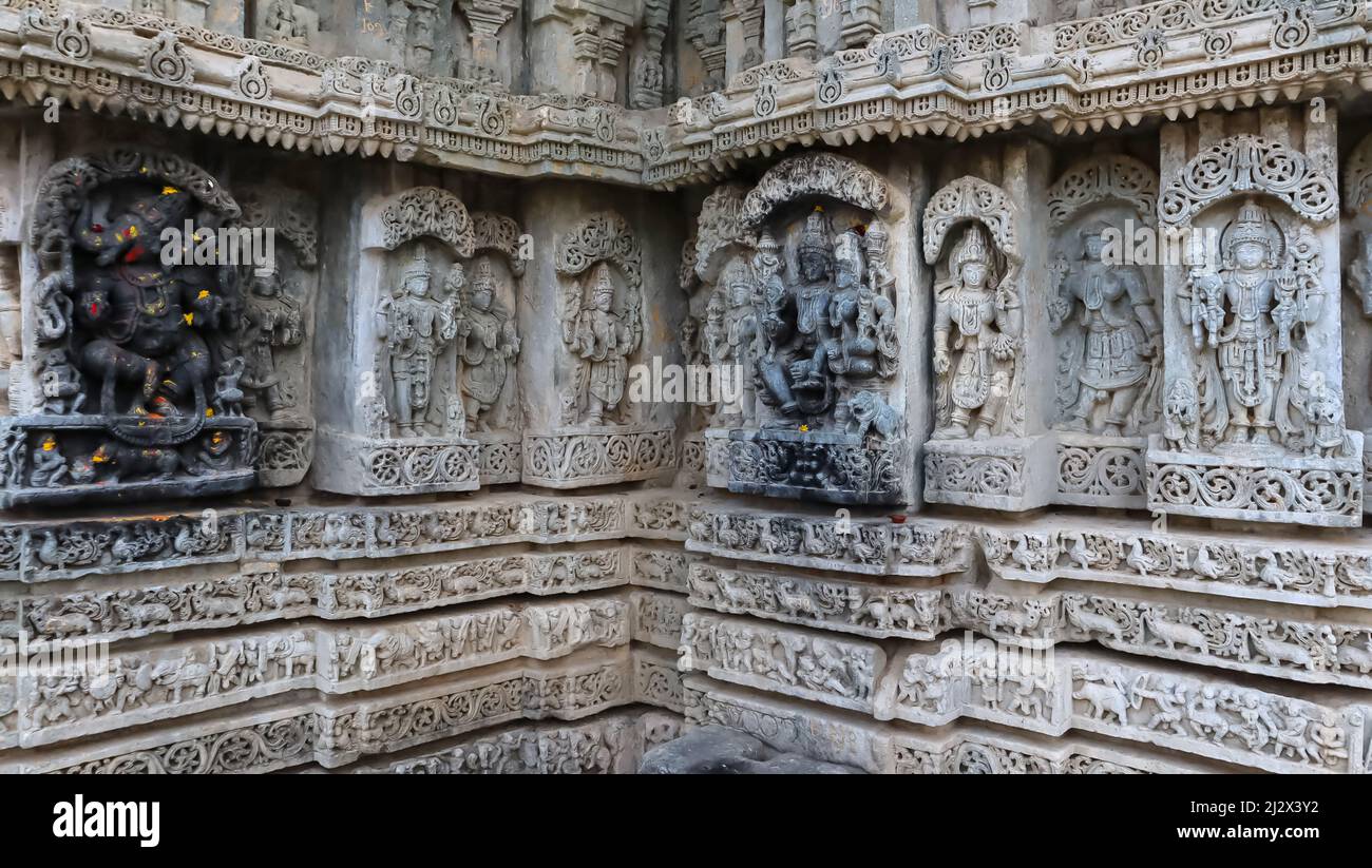 Skulpturen von Lord Ganesha, Lord Shiva und Lord Vishnu mit Kriegsskulpturen an der Wand des javagalen Tempels, Hassan, Karnataka. Stockfoto