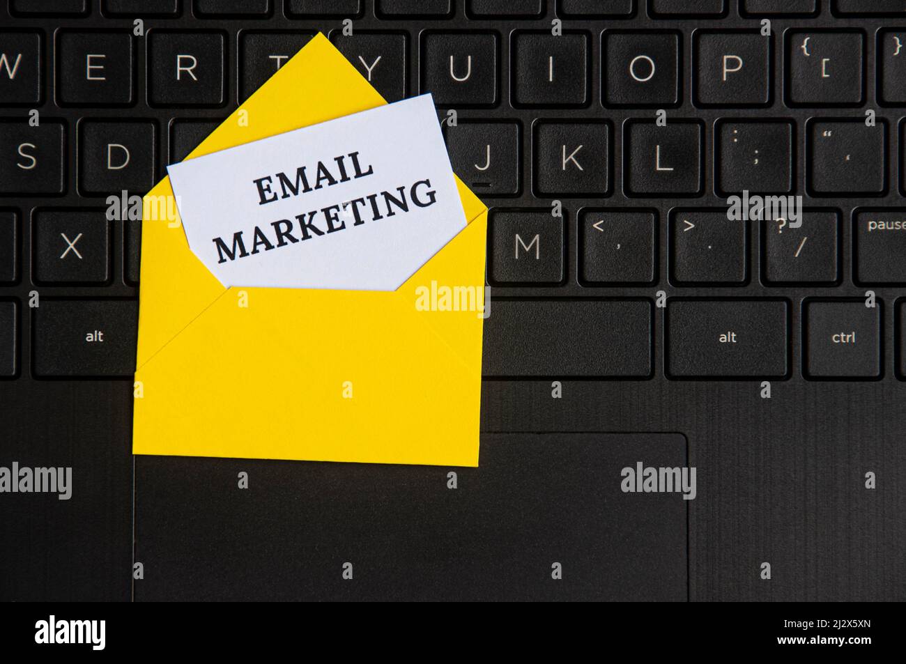 Draufsicht auf E-Mail-Marketing-Text auf Notizblock in einem Umschlag mit Laptop-Hintergrund. E-Mail-Marketing-Konzept Stockfoto