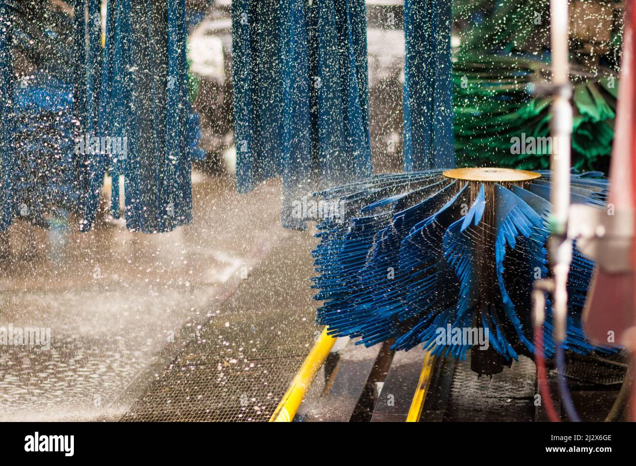 Schuss während der Vorbereitung einer automatischen Autowaschmaschine. Die Waschbürsten drückten Wasser über den ganzen Platz. Stockfoto