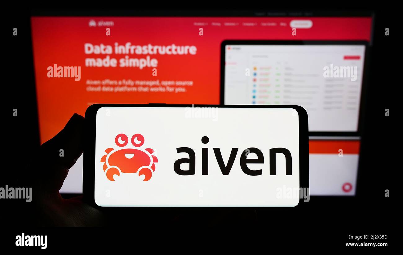 Person, die Smartphone mit Logo des IT-Unternehmens Aiven Oy auf dem Bildschirm vor der Website hält. Konzentrieren Sie sich auf die Telefonanzeige. Stockfoto