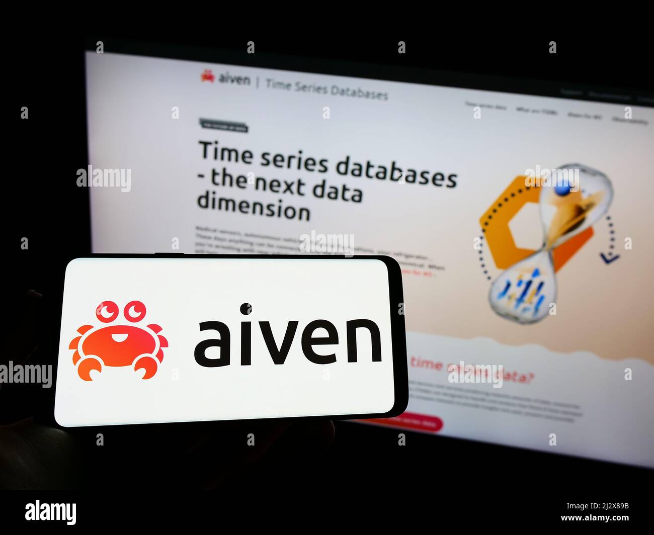 Person, die Mobiltelefon mit Logo des IT-Unternehmens Aiven Oy auf dem Bildschirm vor der Business-Webseite hält. Konzentrieren Sie sich auf die Telefonanzeige. Stockfoto