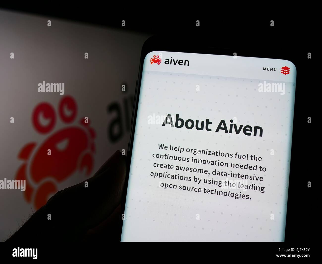 Person, die Mobiltelefon mit der Webseite des IT-Unternehmens Aiven Oy auf dem Bildschirm vor dem Logo hält. Konzentrieren Sie sich auf die Mitte des Telefondisplays. Stockfoto