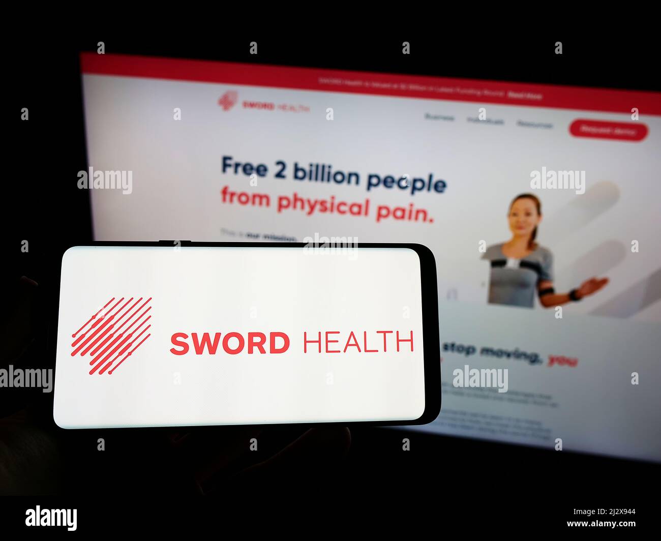 Person, die Mobiltelefon mit dem Logo des E-Health-Unternehmens SWORD Health Inc. Auf dem Bildschirm vor der Business-Webseite hält. Konzentrieren Sie sich auf die Telefonanzeige. Stockfoto