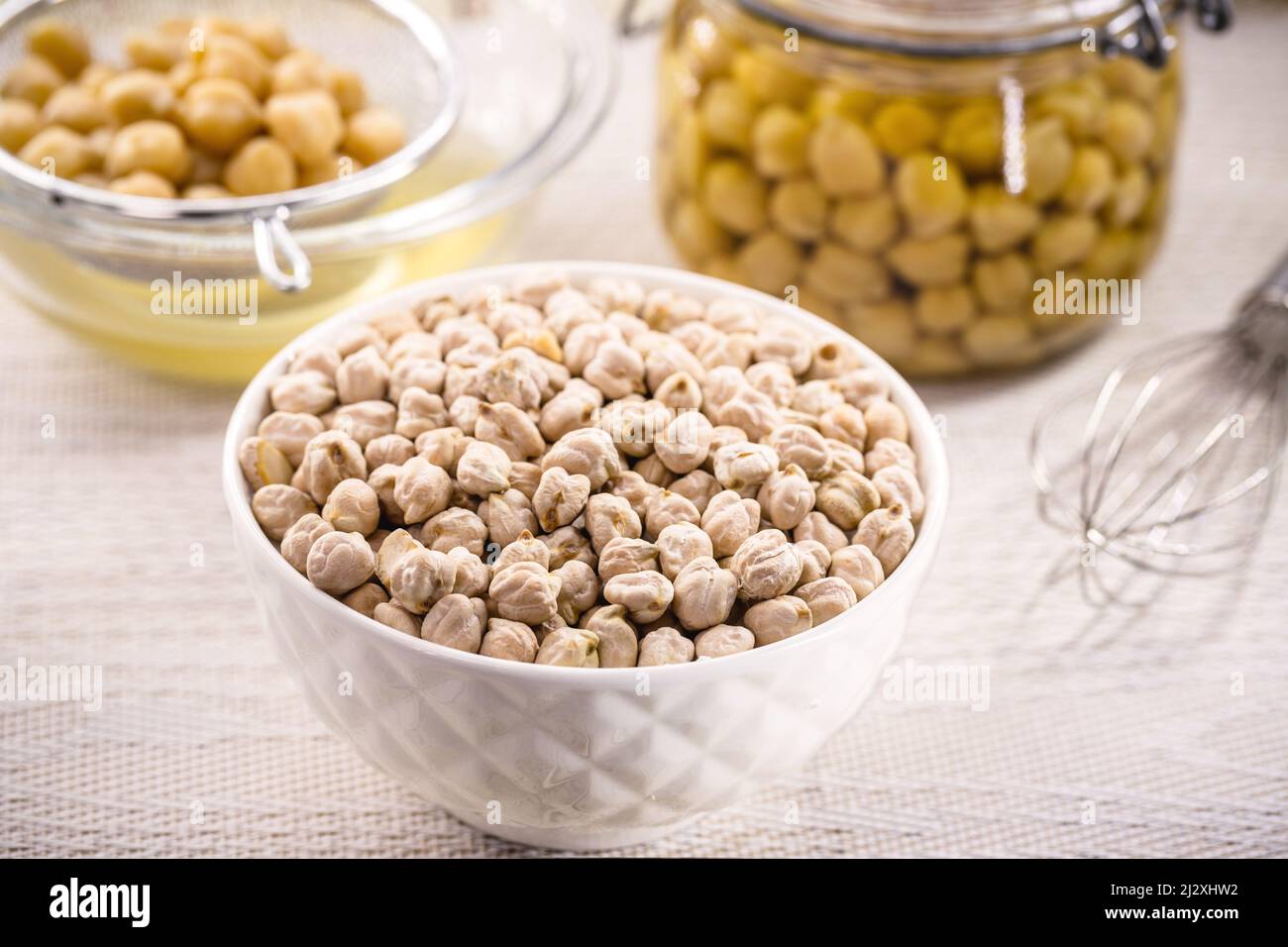 Rohe und getrocknete Kichererbsen-Samen in weißer Schale, vegane Zutat für Aquafaba und andere Mahlzeiten, natürliche Faserersatzquelle Stockfoto