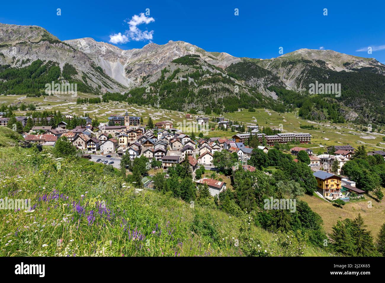 Kleine alpine Stadt Bersezio auf dem grünen Tal zwischen Bergen unter blauem Himmel im Piemont, Norditalien. Stockfoto