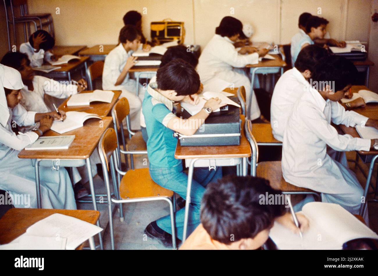 Saudi-Arabien Ex-patt Boy Writing in Class Lehing on his Briefcase at School (1970er Jahre) Stockfoto