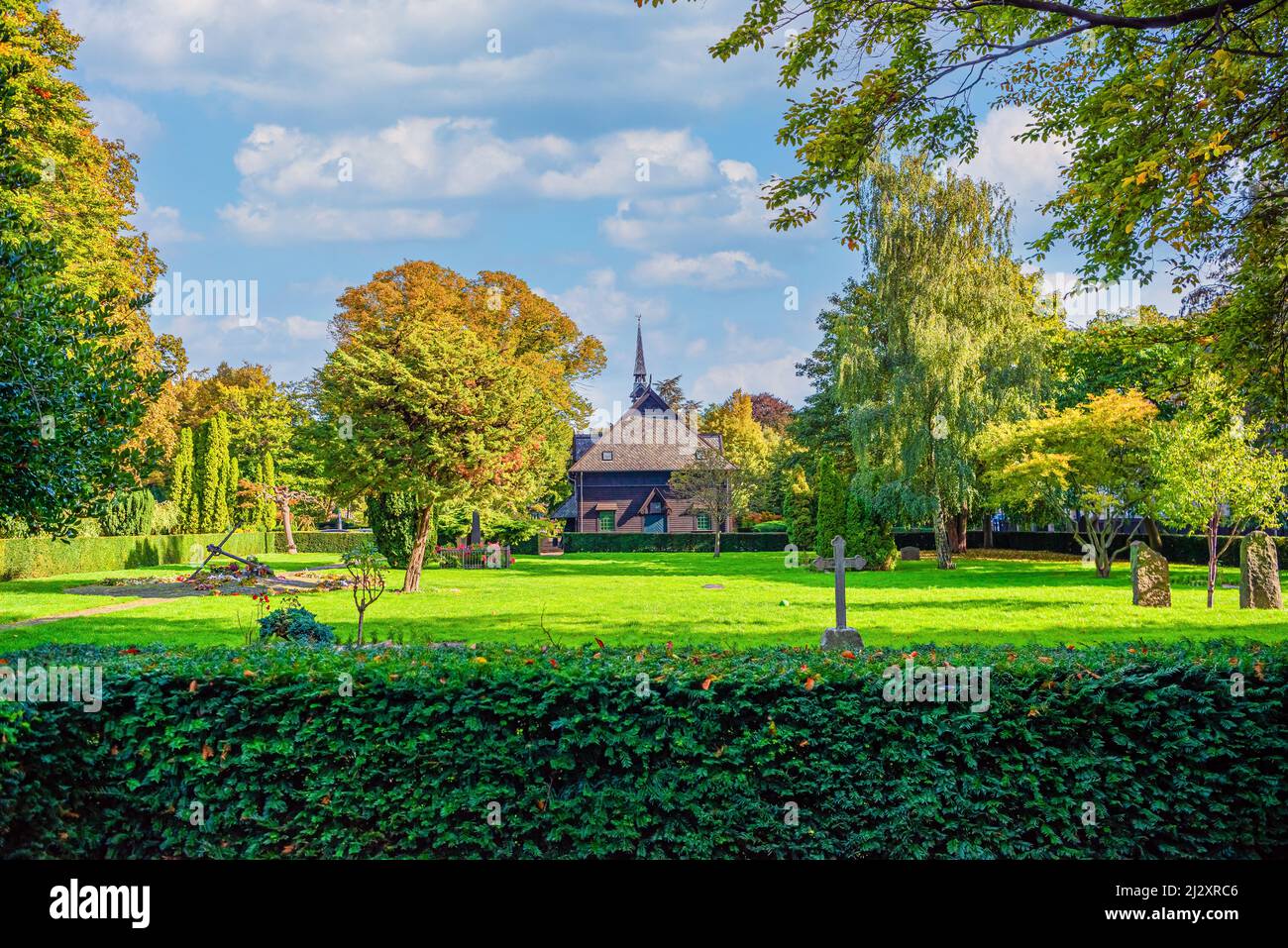 Viele grüne Bäume, Sträucher, Blumen und eine alte Kapelle auf dem Holmen Friedhof. Kopenhagen, Dänemark Stockfoto