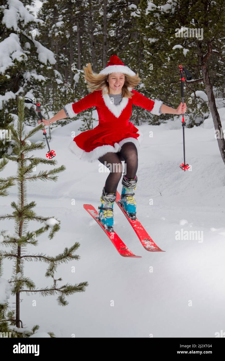 Frau trägt ein Weihnachtsmann oder Mutter Weihnachtskostüm und Skifahren in einem Wald-Skispringen Stockfoto