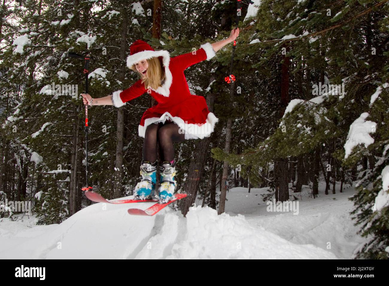 Frau trägt ein Weihnachtsmann oder Mutter Weihnachtskostüm und Skifahren in einem Wald-Skispringen Stockfoto