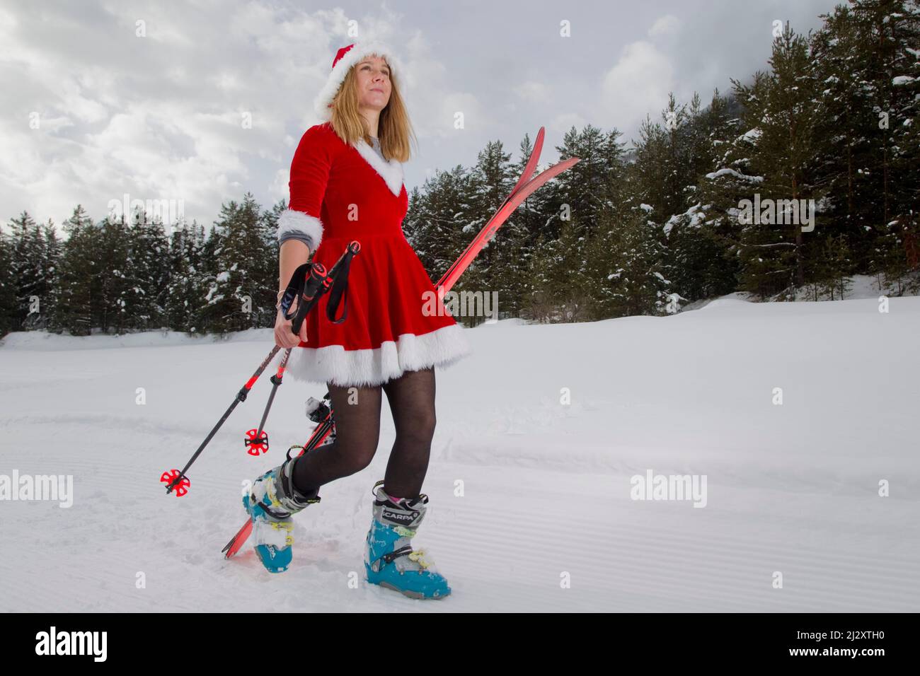 Frau mit Weihnachtsmann- oder Mutter-Weihnachtskostüm und Skifahren in einem Wald Stockfoto