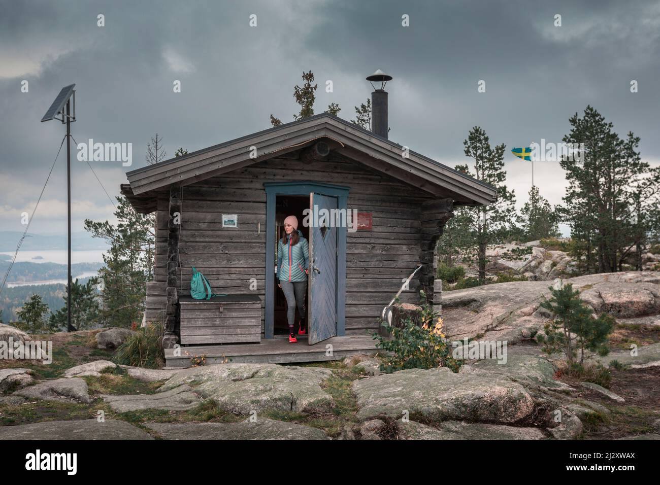 Frau öffnet die Tür der Zuflucht auf dem Gipfel des Valkallen in Höga Kusten im Osten Schwedens Stockfoto