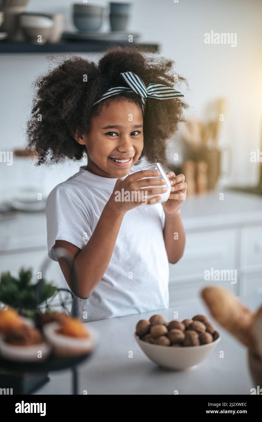 Nettes dunkelhäutig Mädchen mit einem Glas Milch Stockfoto