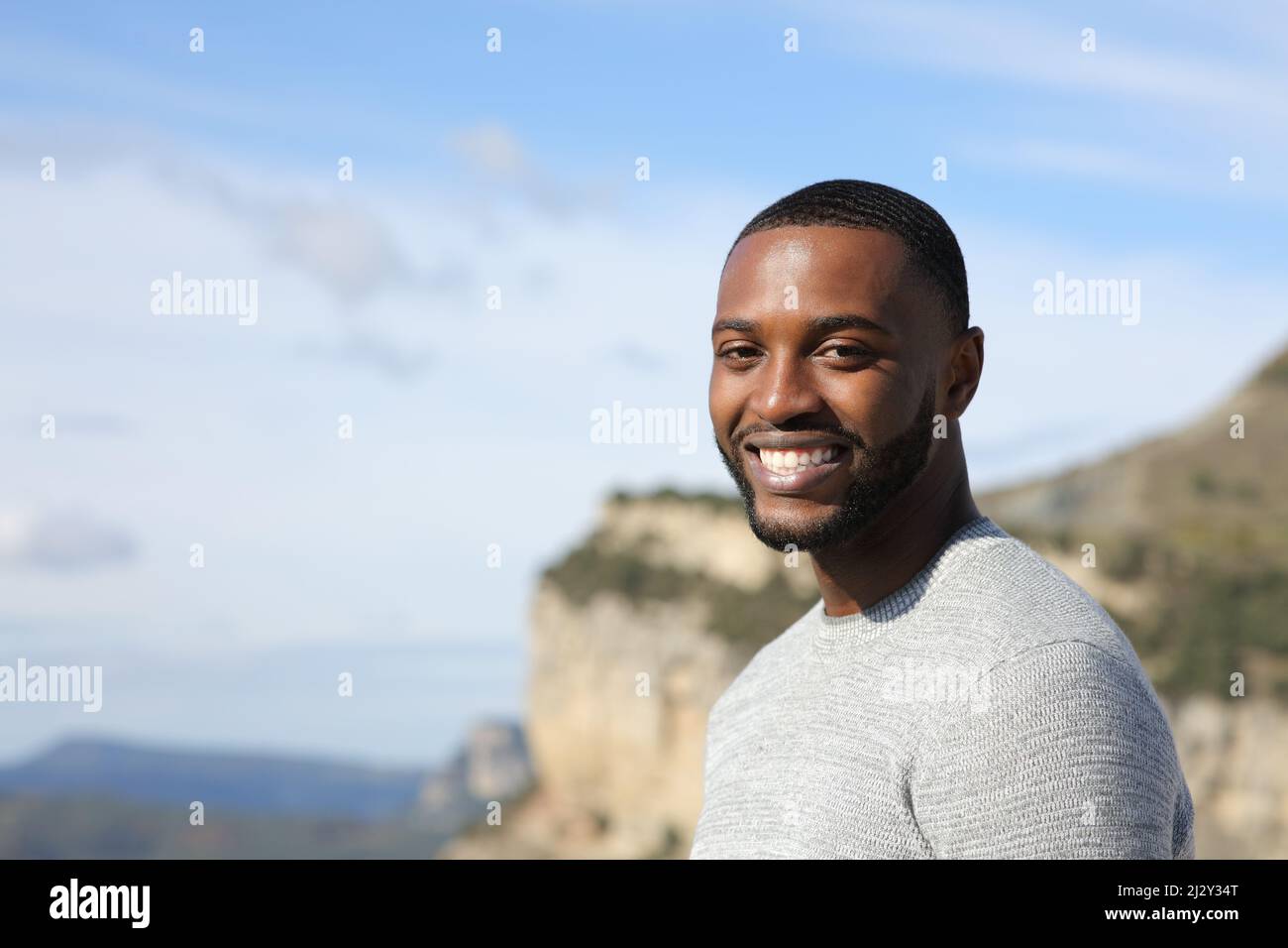 Porträt eines hübschen glücklichen Mannes mit schwarzer Haut, der in der Natur die Kamera anschaut Stockfoto