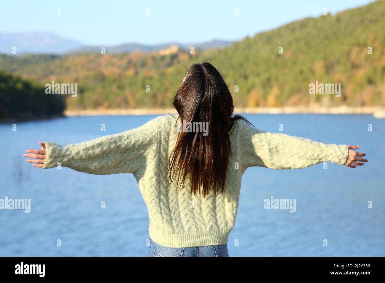 BAK-Blick auf eine Frau, die ihre Arme ausstreckt und Urlaub im Winter in der Natur feiert Stockfoto