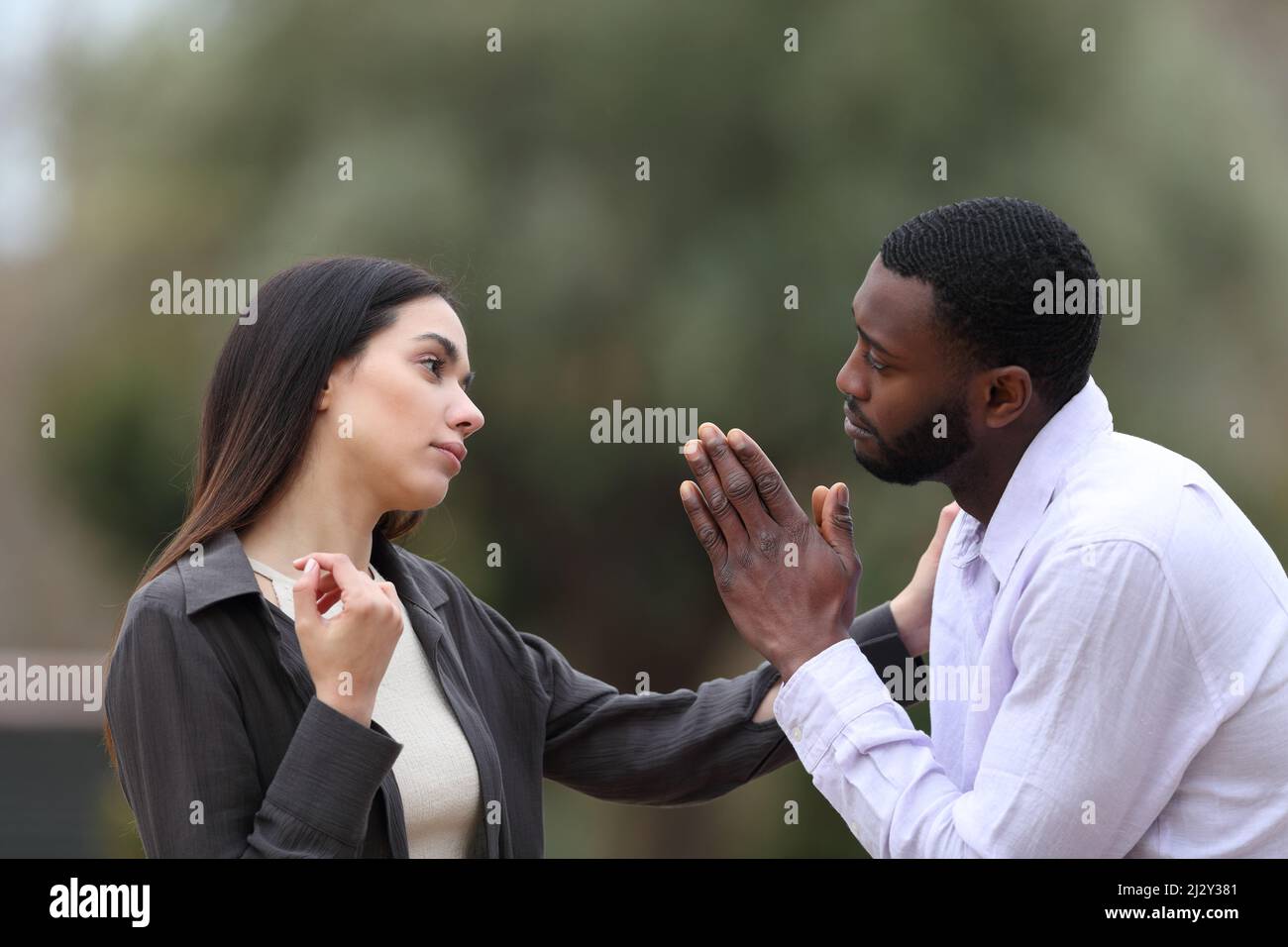 Bedauernswerter Mann, der eine Frau in einem Park um Vergebung bittet Stockfoto