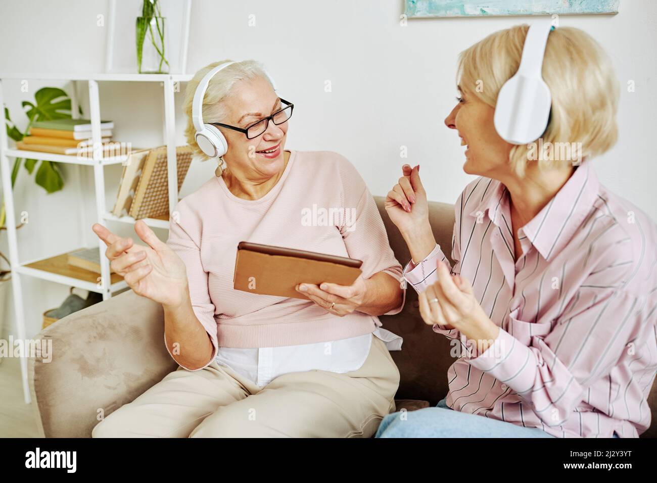 Porträt einer erwachsenen Tochter mit Mutter, die gemeinsam tanzt und Musik in Kopfhörern hört Stockfoto