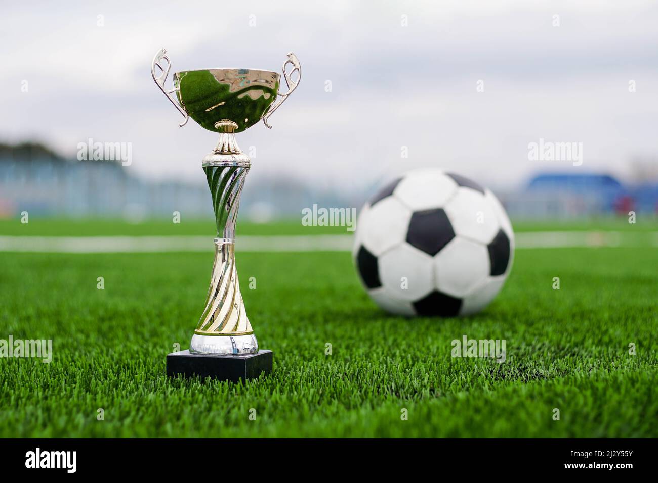 Goldene Fußballpokal mit Fußball auf dem Spielfeld. Stockfoto