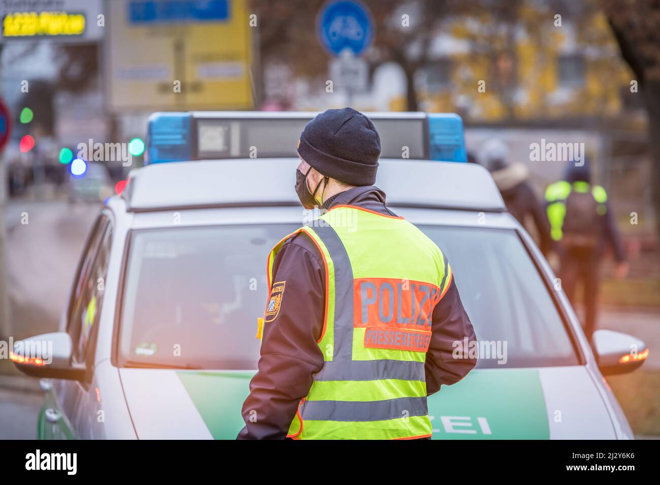 Regensburg, Bayern, 26. Januar 2022: Polizei-Pressereferent vor einem Polizeiauto-Einsatzfahrzeug mit blauem Licht während einer Anti-Korona Stockfoto