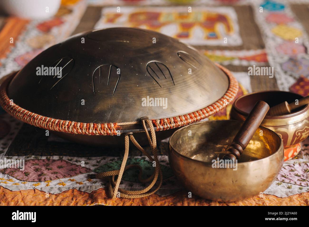 Zungentrommel und tibetische Schalen liegen auf dem Teppich. Stockfoto