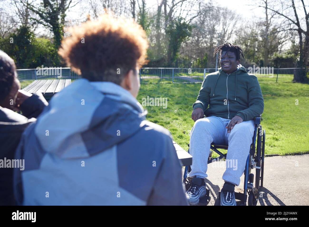 Teenage Boy In Wheelchair Aufhängen Reden Und Lachen Mit Freunden Im Park Stockfoto