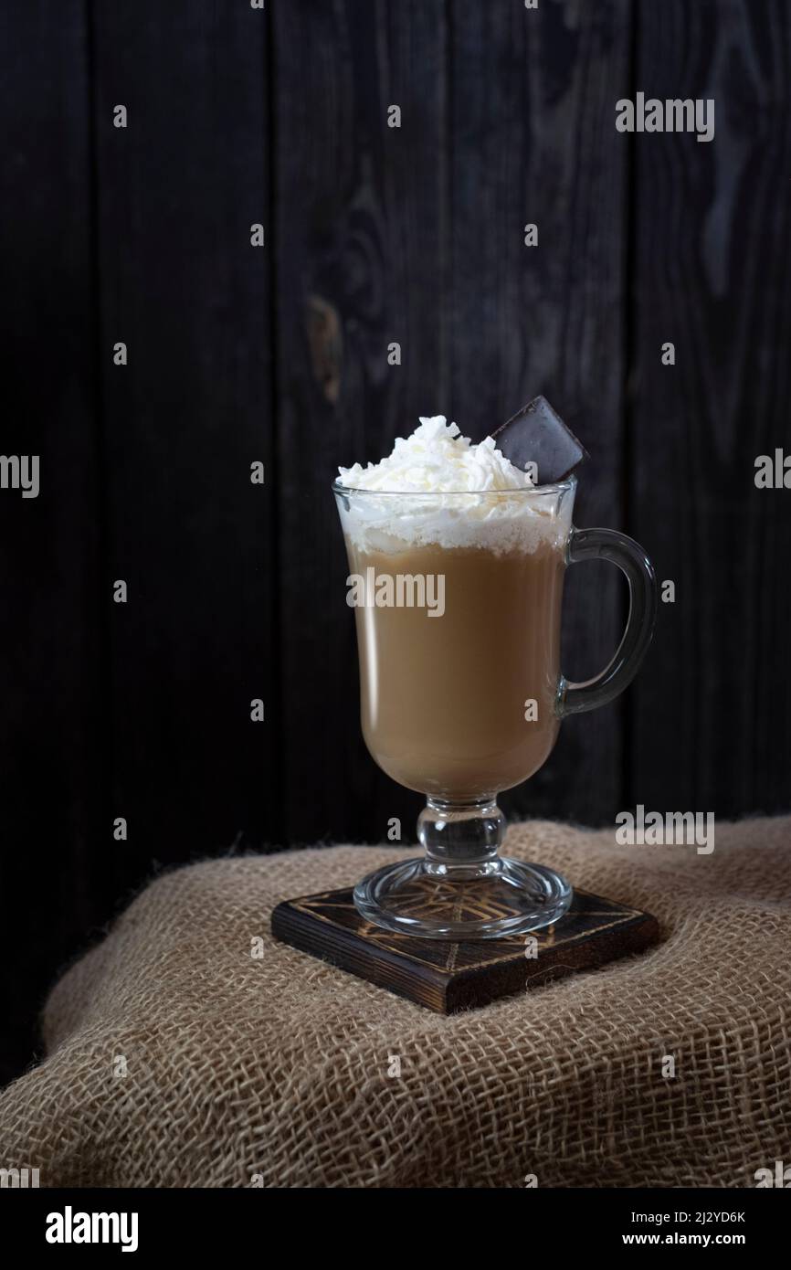 Kaffee mit Milch mit Rahm und Schokolade auf dunklem Holzhintergrund im rustikalen Stil Stockfoto