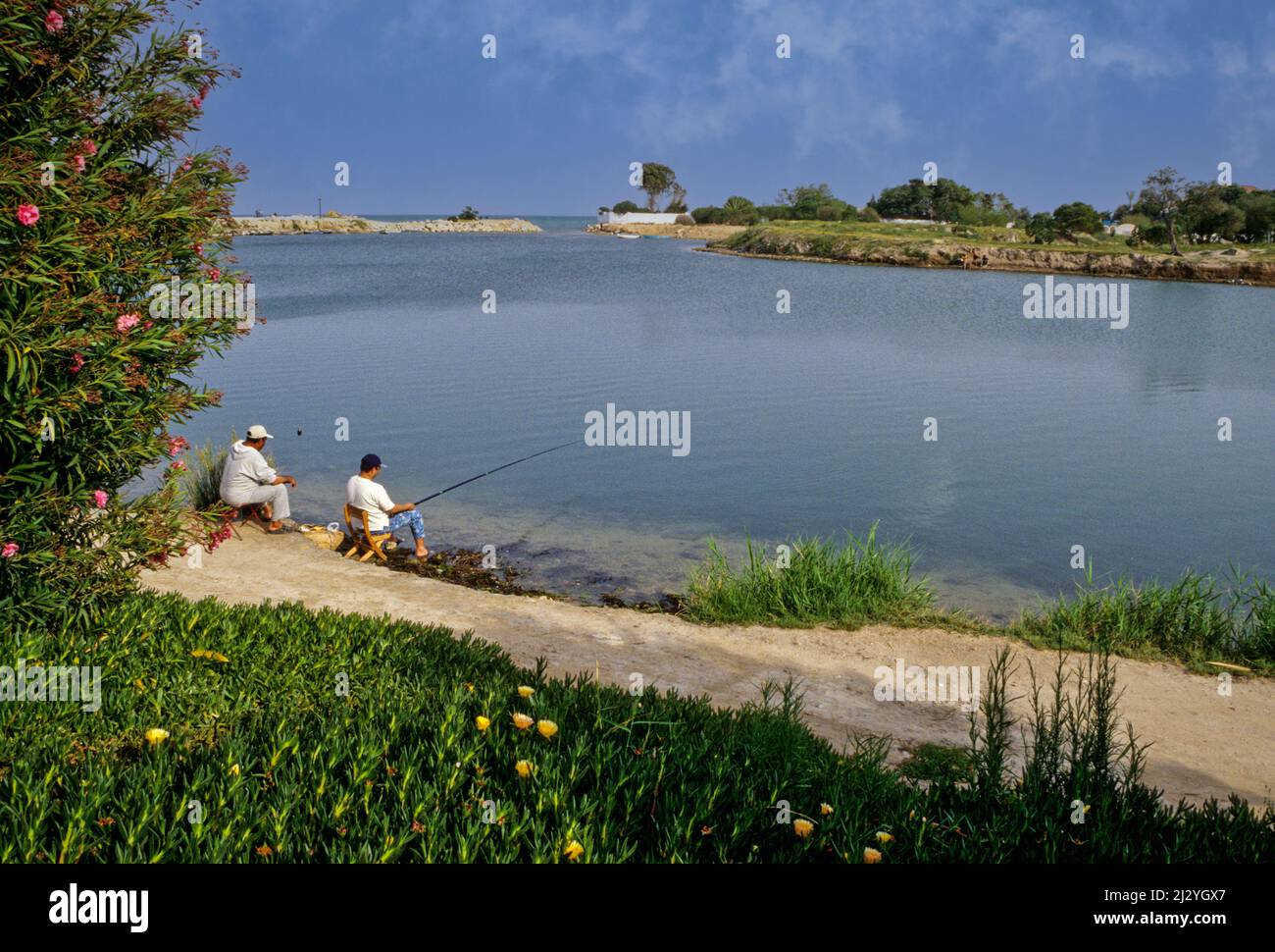 Karthago, Tunesien.  Punische Häfen, Datum jetzt kleine Seen, umgeben von luxuriösen Häuser ähneln vom 4.. Jahrhundert v. Chr.  Dies war der Marine oder Militär, Hafen.  Ein Handelshafen grenzt.  Männer angeln. Stockfoto