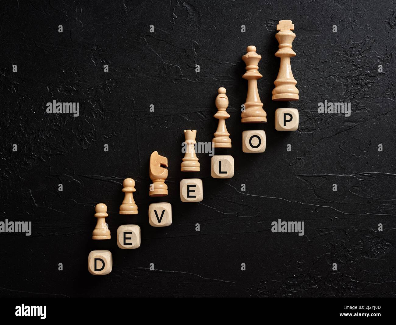 Das Wort entwickeln sich auf Holzwürfeln mit Schachfiguren. Geschäftsentwicklungskonzept. Stockfoto
