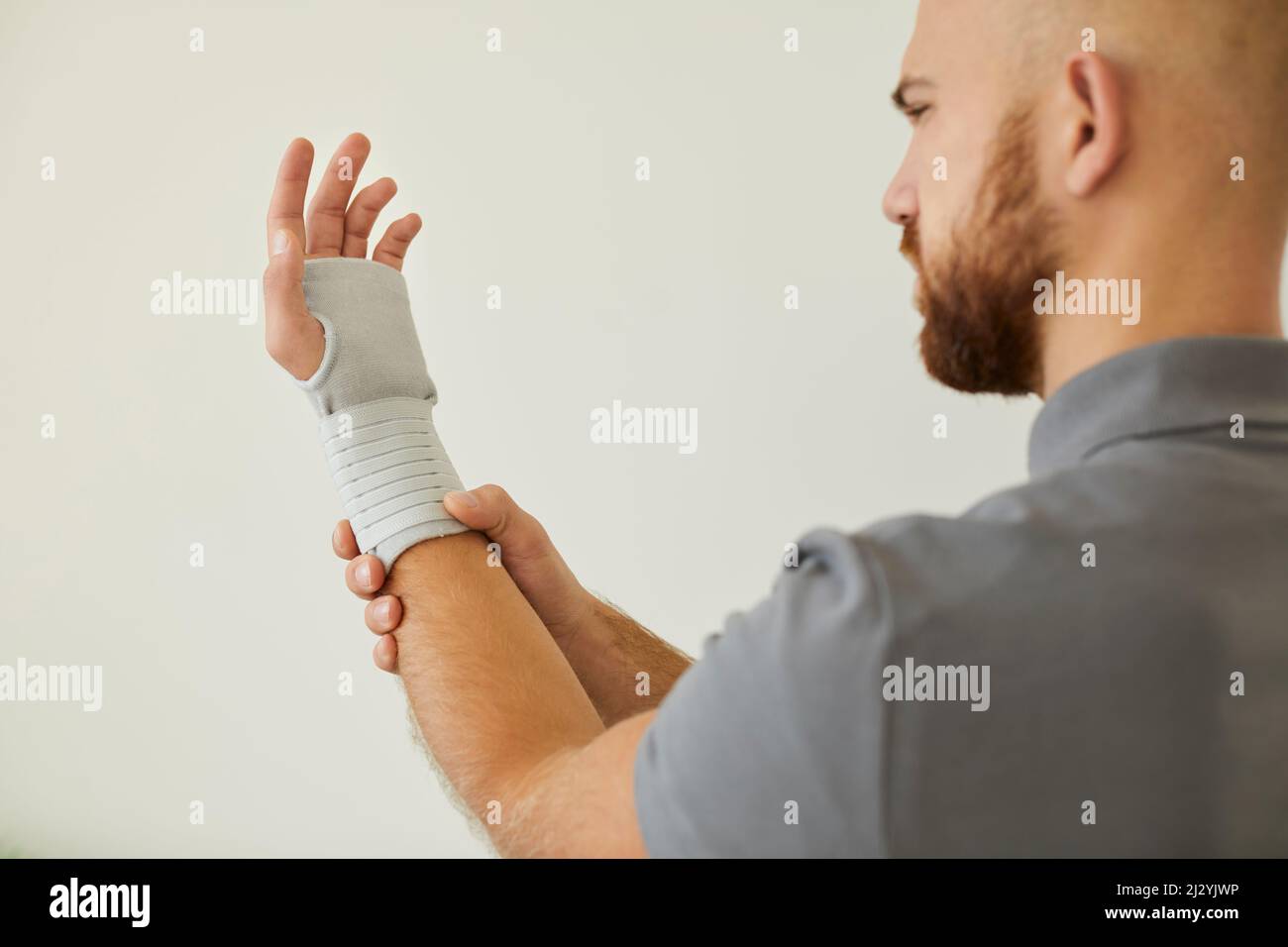 Der Mensch verwendet medizinische Verbandsmaterial für das Handgelenk als vorbeugende Maßnahme für Sport oder körperliche Aktivität. Stockfoto