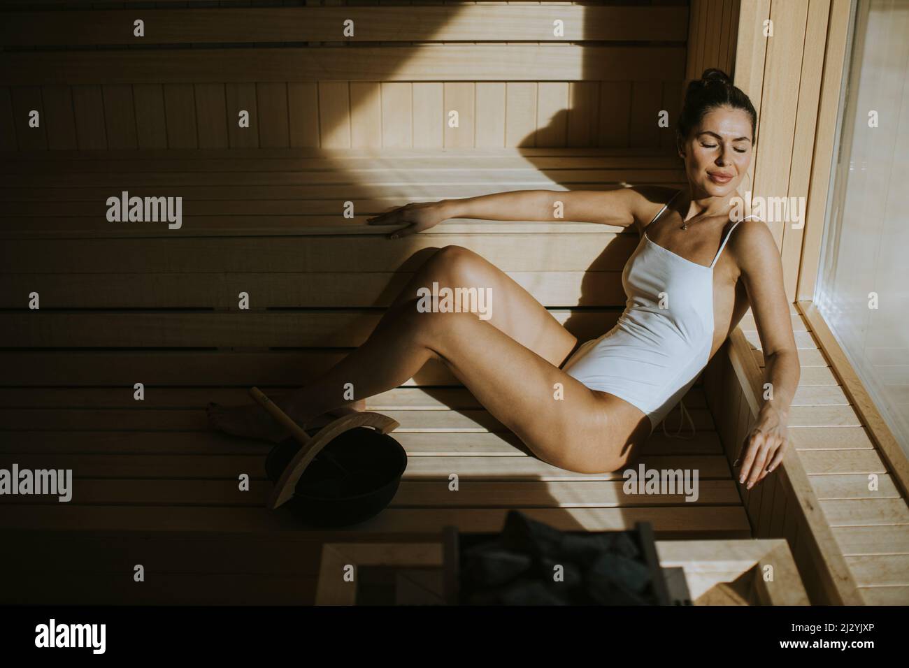 Attraktive junge Frau, die sich in der Sauna entspannt Stockfoto