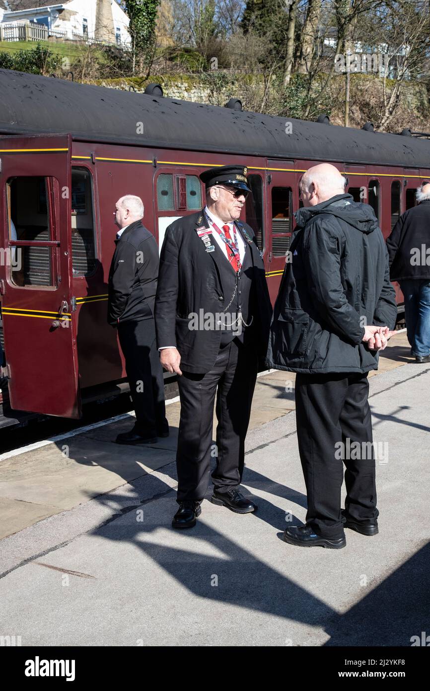 Bahnhofmeister und Bahnbeamter unterhalten sich auf der Oxenhope-Plattform vor der Abfahrt des Worth Valley-Dampfzuges nach Keighley Stockfoto