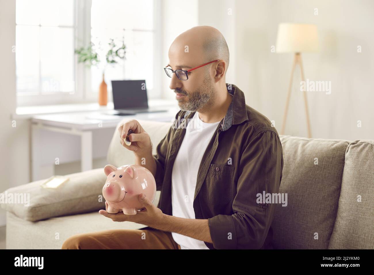 Vorseher Mann legte Münze in Sparschwein Stockfoto