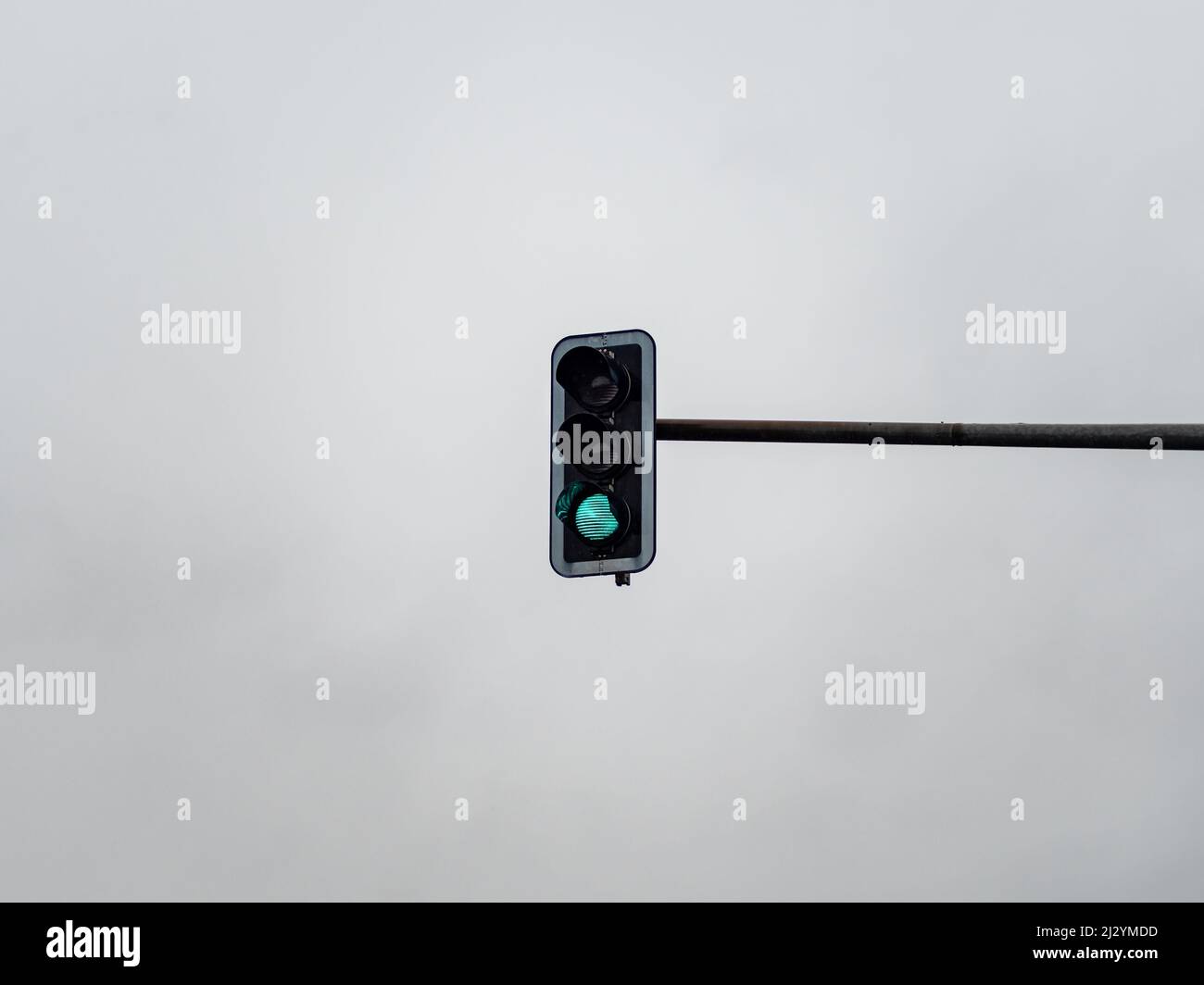 Grünes Ampelsignal vor einem bewölkten Himmel. Lichtsymbol, um die Autos auf der Straße zu steuern und den Straßenbenutzer zu führen. Go-Schild Stockfoto