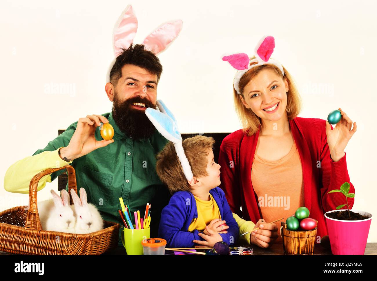 Ostertag. Glückliche Mutter, Vater und Sohn mit bemalten bunten Eiern. Kaninchenfamilie in Hasenohren. Stockfoto