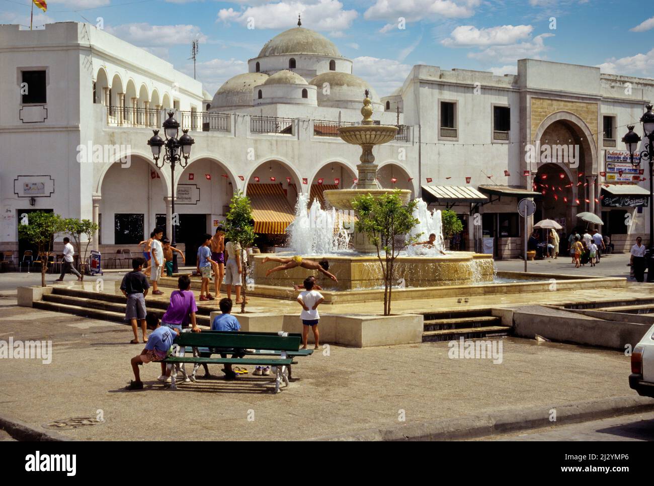 Tunis, Tunesien.  Sidi Mehrez Moschee (1675-92), aus dem Ort Bab Souika.  Kinder spielen in Nachbarschaft Brunnen.  Bab Souika Eingang zur Medina auf rechten Seite. Stockfoto