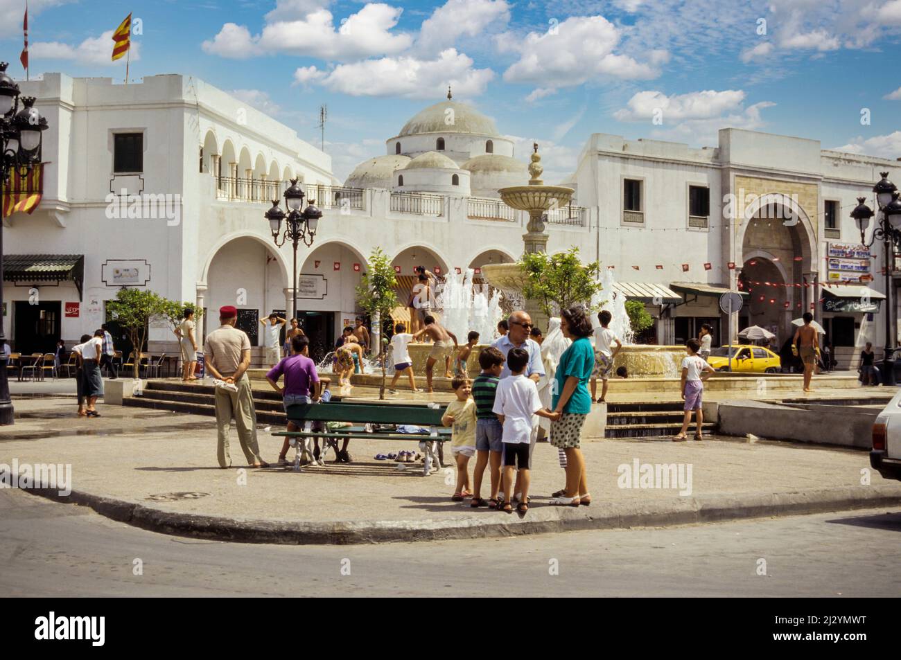Tunis, Tunesien.  Sidi Mehrez Moschee (1675-92), aus dem Ort Bab Souika.  Kinder spielen in Nachbarschaft Brunnen.  Bab Souika Eingang zur Medina auf rechten Seite. Stockfoto