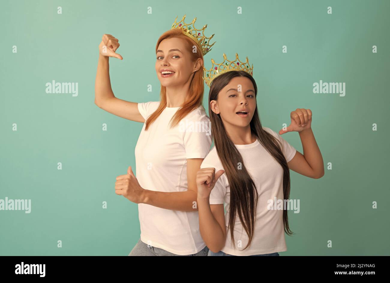 Glückliche Frau und Mädchen in Kronen zeigen die Finger auf Werbe-T-Shirts für Kopierer, Werbung Stockfoto