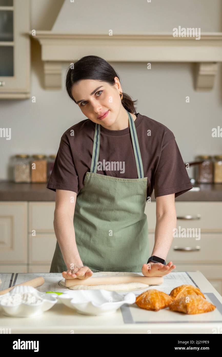 Nette junge Brünette Frau in einer Küchenschürze kocht in der Küche. Stockfoto