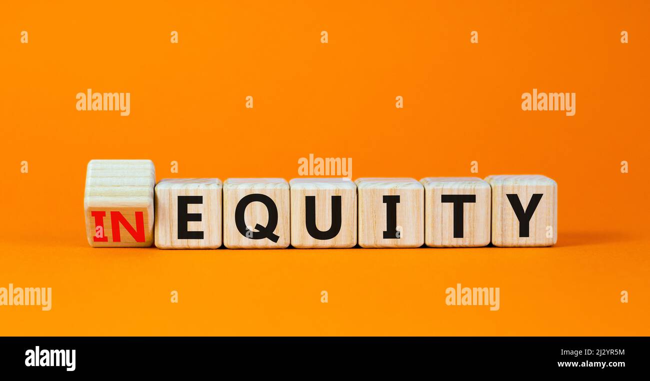 Symbol für Ungleichheit oder Eigenkapital. Drehten Holzwürfel und änderten das Konzeptwort InEquity in Equity. Schöne orange Tisch orange Hintergrund. Business und Stockfoto