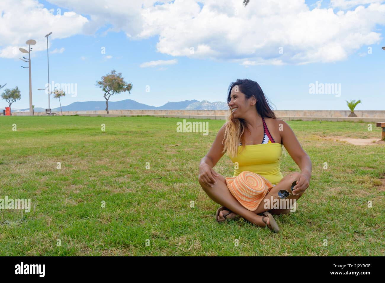 Porträt einer lateinischen Frau, die lächelt, Spaß hat, im Urlaub auf mallorca, posiert an einem warmen Sommertag im Frühling, unter einer Palme, Ferienkonzept Stockfoto