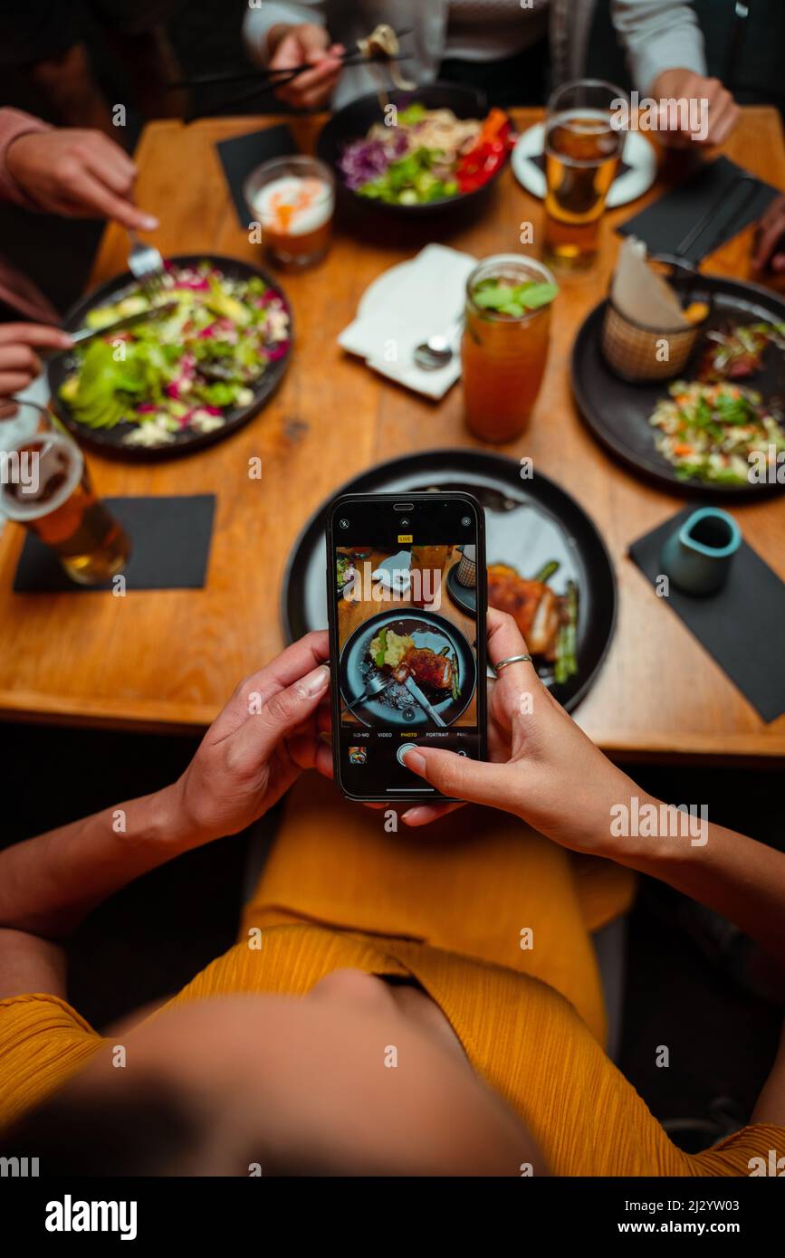 Freunde zum Abendessen unterwegs und Fotos vom Essen machen Stockfoto
