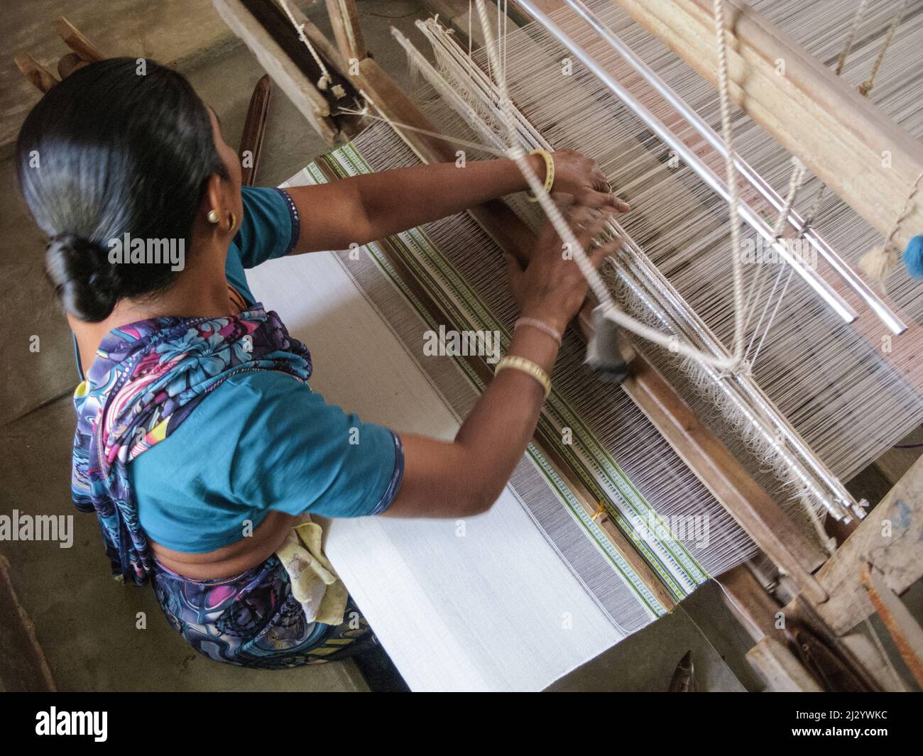 Indien, Gujarat, Kutch, Handloom Design Center in Bhujodi. Frau, die an einem Stechloch arbeitet, das Textilien webt. Ihre Füße liegen unter Bodenniveau. Stockfoto