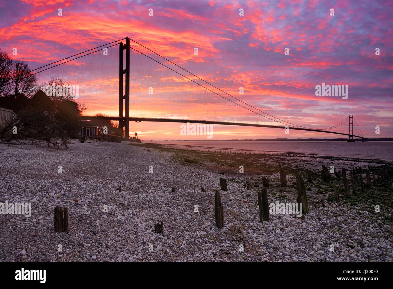 Sonnenaufgang am roten Himmel auf der Humber Bridge in der Nähe von Kingston upon Hull, East Riding of Yorkshire, England. Eine einspannige Hängebrücke für die Straße. Stockfoto