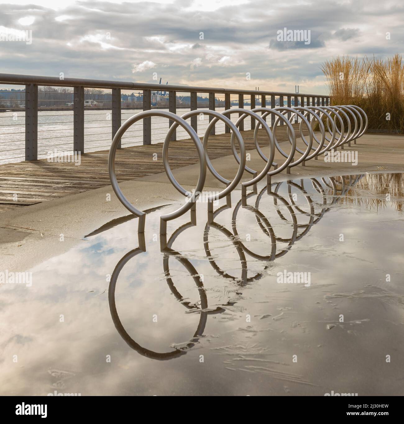 Moderner Fahrradständer mit Spiegelung nach Regen auf der Straße einer Stadt. Niemand, selektiver Fokus, Straßenfoto Stockfoto