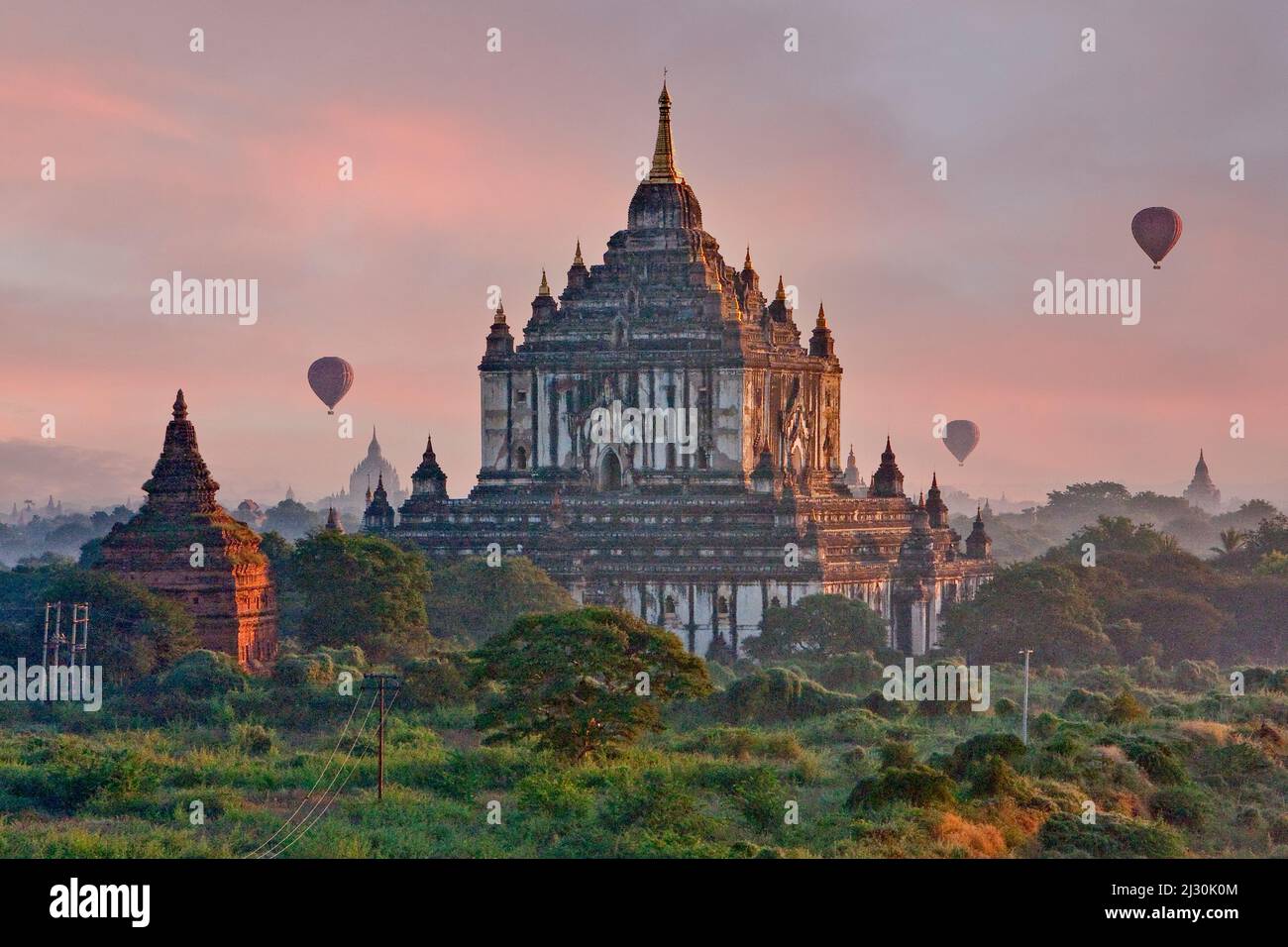 Myanmar, Burma, Bagan. Am frühen Morgen beginnen sich Heißluftballons über dem Thatbyinnyu-Tempel zu erheben. Stockfoto